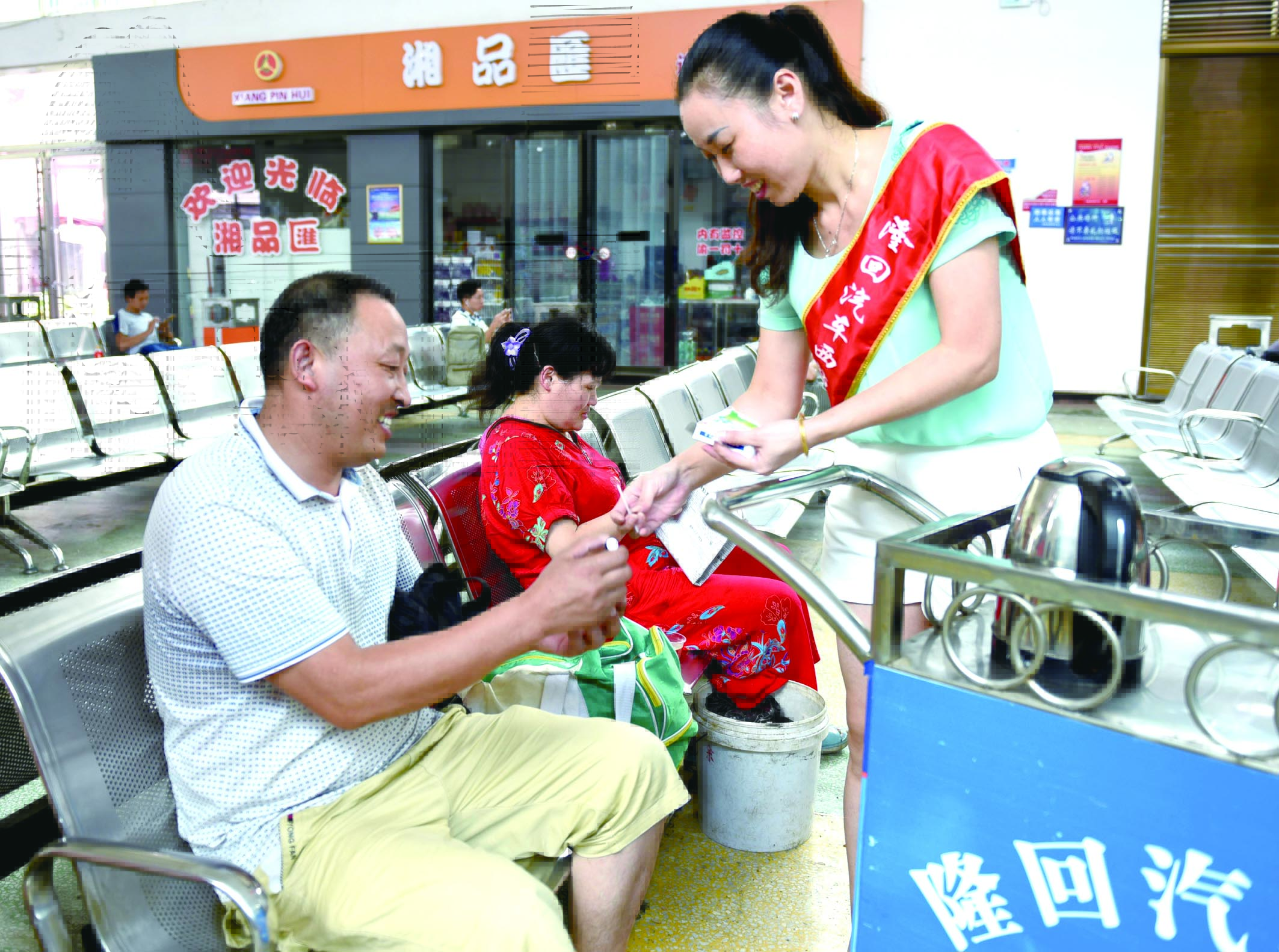 隆回分公司汽車西站工作人員正在為旅客免費(fèi)贈(zèng)送藿香正氣水。